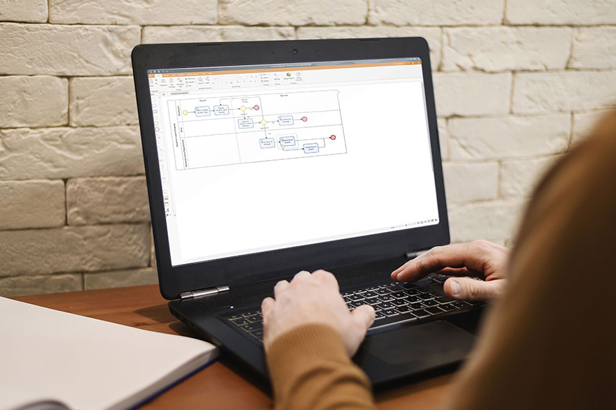 Person at desk building business process map in Bizagi Modeler on laptop