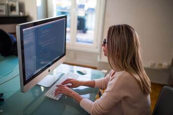 Woman working on PC at desk in home office