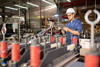 Young factory engineer or technician with tablet browsing in the net for technical information about new industrial equipment