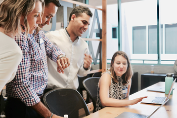 Woman at desk surrounded by colleagues