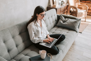 Woman sat on sofa using laptop