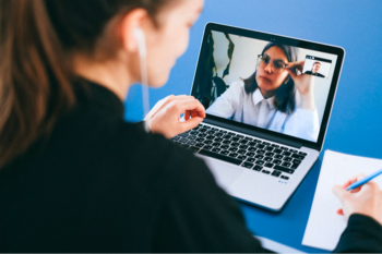Woman making notes on video call on laptop