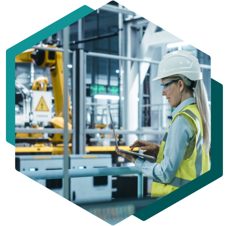 Woman in safety clothing working on laptop in factory