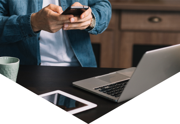 Man standing at desk typing on smartphone