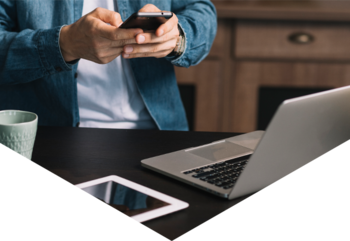 Man standing at desk typing on smartphone