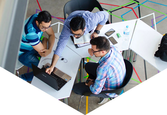 Three men sat at desk looking at laptop screen
